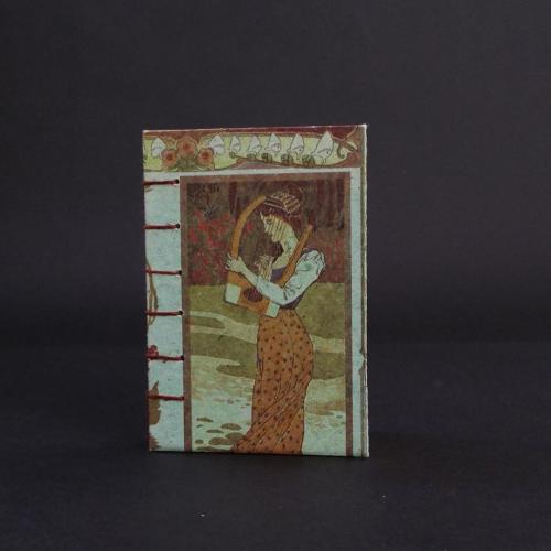 Art Nouveau Lady Coptic bound journal cover featuring a 3/4 shot of a lady in an orange dress holding a harp.