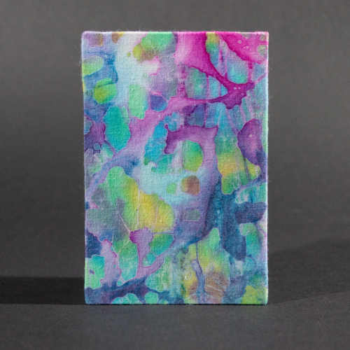 The front cover of the blue batik medium accordion book with blue, pink, and yellow organic shapes