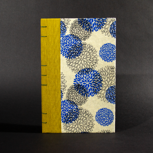 Front cover of blue floral lined quarto Coptic bound journal with gold bookcloth on the spine and and blue and black flowers on an ivory background