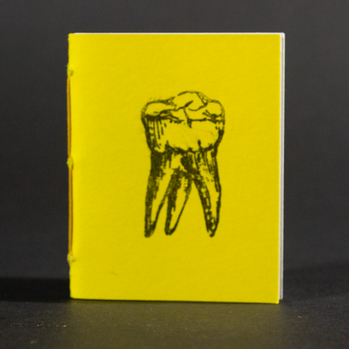 A single yellow tooth is on the cover of this mini pamphlet book