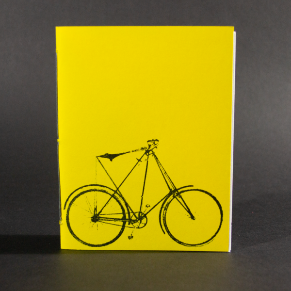 Pamphlet binding class sample of a bound book with a yellow cover and a bicycle in black on the cover.